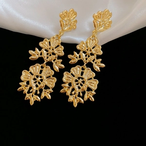 Macro view of vintage gold hollow flower drop earrings with matte embossed texture
