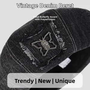 Detailed close-up of dark denim beret featuring silver metal butterfly and frayed patch