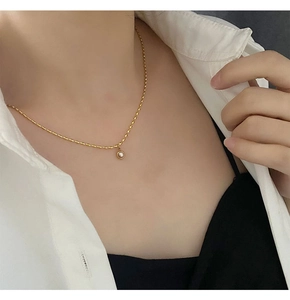 Close-up of a delicate gold titanium steel necklace with a purple pearl pendant on a model