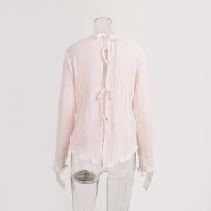 Detail view of pink pleated blouse featuring back tie closure and flared wave hem