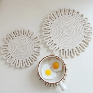 Detailed view of three off-white woven cotton table mats with flower edge design