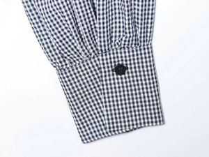 Detail of gingham shirt sleeve with black button and woven fabric texture