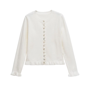 Close-up of white knit cardigan showing pearlescent buttons and ruffled hem detailing