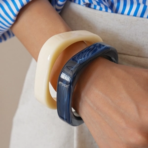 Close-up of retro resin geometric square bangles in cream and marble blue worn on wrist