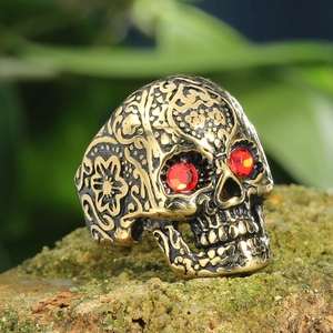 Retro mens skull ring in antique bronze with red gemstone eyes on mossy rock