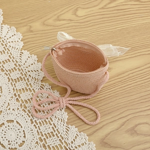Detail view of pink woven straw crossbody bag with sweet lace bow and metal zipper