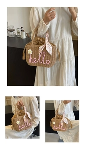 Detail of woven straw bag with pink hello lettering and floral silk scarf accessory