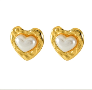 Macro detail of French vintage heart studs with gold hammered texture and white pearl core