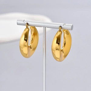 Macro shot of polished gold-toned hollow C-shaped earrings on a silver jewelry stand