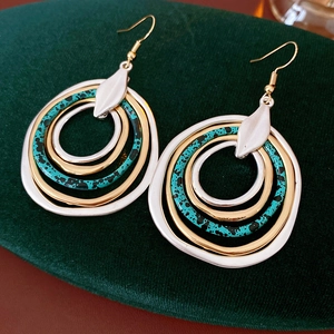 Detailed view of multilayer irregular round hook earrings with gold, silver and green finish