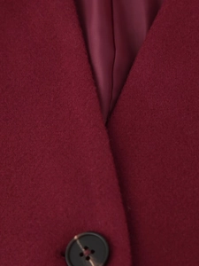 Detailed macro view of dark red wool coat fabric texture and glossy brown button
