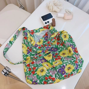 Flat lay of floral canvas tote bag with strawberry prints and everyday accessories
