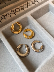 Detail of gold and silver hoop earrings with marquise zircon on a jewelry tray