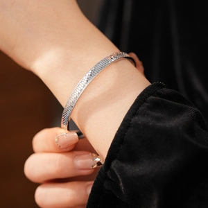 Macro shot of silver bangle featuring a textured honeycomb pattern on a model's wrist