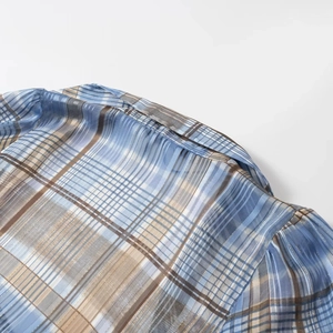 Detail of blue and brown plaid shirt fabric with gold metallic thread and stitching