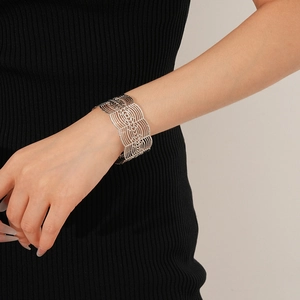 Détail d'un large bracelet manchette argenté avec texture dentelle vintage au poignet