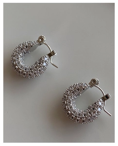 Macro shot of silver U-shaped earrings encrusted with sparkling zircon stones
