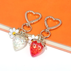 Detailed view of colorful strawberry keychains with daisy charms and gold heart clasps