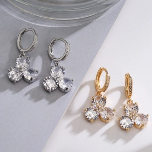 Eleganti orecchini a fiore in oro e argento con cristalli di zircone su sfondo grigio