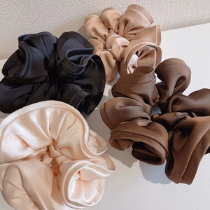 Detailed view of satin scrunchies in black, champagne, dark brown, and creamy white colors