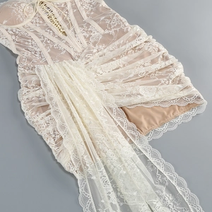 Detail of white lace dress featuring criss-cross front lacing and tiered ruffles