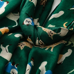 Detailed macro view of dark green scarf fabric with cute beige and blue cartoon cat patterns