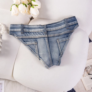 Piatto di pantaloncini di jeans blu a vita alta su divano bianco con perle e rose