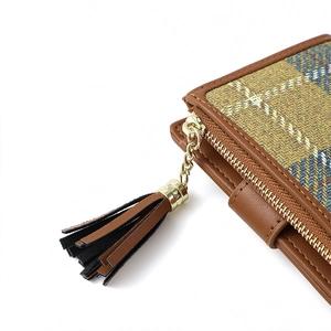 Detail of brown leather trim with yellow-blue plaid fabric and a leather tassel puller