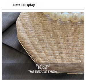 Macro detail of golden sequin fabric and large pearl handle on luxury evening clutch