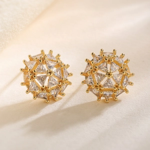 Boucles d'oreilles étoiles plaquées or serties de zircons triangulaires sur fond de tissu doux