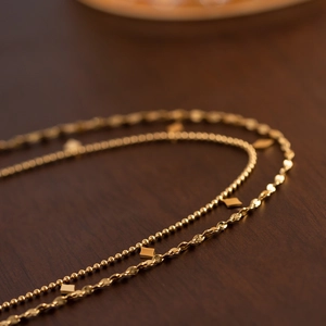 Macro shot of double-layered gold tassel necklace with beads and square charms