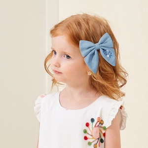 Nœud pour cheveux en lin bleu clair avec broderie florale porté par une fille