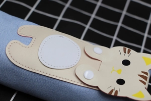 Close-up of a cute cartoon cat button closure on a light blue canvas pencil case