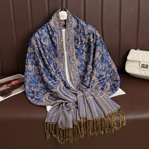 Detailed view of paisley patterns and fringes on a luxury blue cashmere-like shawl scarf