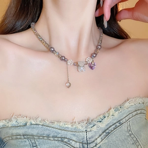 Close-up of a purple heart crystal and clear bear pendant on a beaded necklace