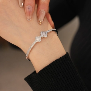 Macro shot of silver four-leaf clover bracelet with white zircon pave setting on wrist