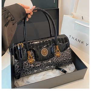 Detail of luxury leopard print handbag with gold animal hardware in a gift box packaging