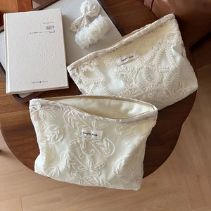 Vue détaillée de la broderie en dentelle florale blanche sur des trousses à maquillage