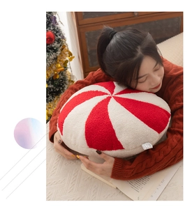 Close-up of a soft red and white peppermint candy plush pillow for Christmas decor