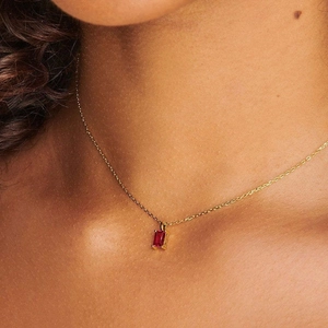 Detail shot of a 18K gold plated necklace with a rectangular red zircon stone pendant