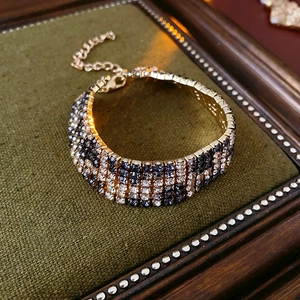 Detail of checkered rhinestone bracelet with golden base on a vintage green cushion