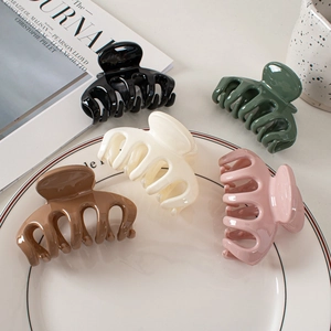 Polished large shark hair clips in five colors arranged on a white ceramic plate