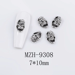 Detailed view of silver skull nail charms with rhinestones on a white mannequin nail