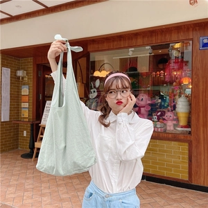 Detail of mint green cotton tote bag showing natural fabric texture and shoulder strap