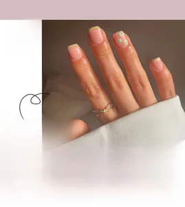 Detail view of yellow French press-on nails with white floral pattern and pink base