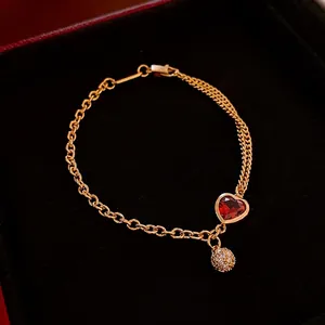 Gold plated double-strand bracelet with red heart stone and pavé ball on black velvet