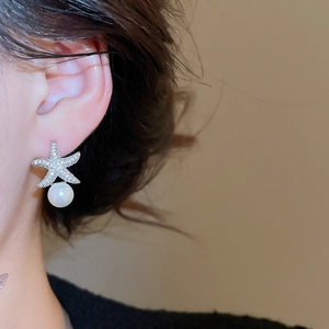 Gros plan de boucles d'oreilles étoile en zircon et perle pendante sur mannequin