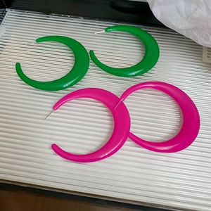Detailed view of large C-shaped geometric resin earrings in green and rose pink colors