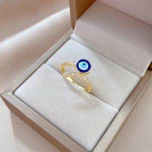 Détail de bague œil en or avec émail bleu et zircons sur fond en soie de luxe