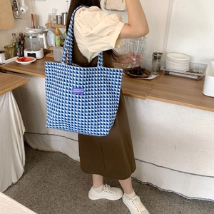 Detail of blue and white checkered wool tote bag with purple label on shoulder strap